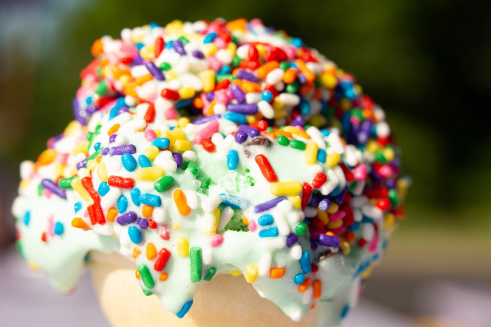 Extreme close-up of a melting ice cream cone covered in rainbow sprinkles.