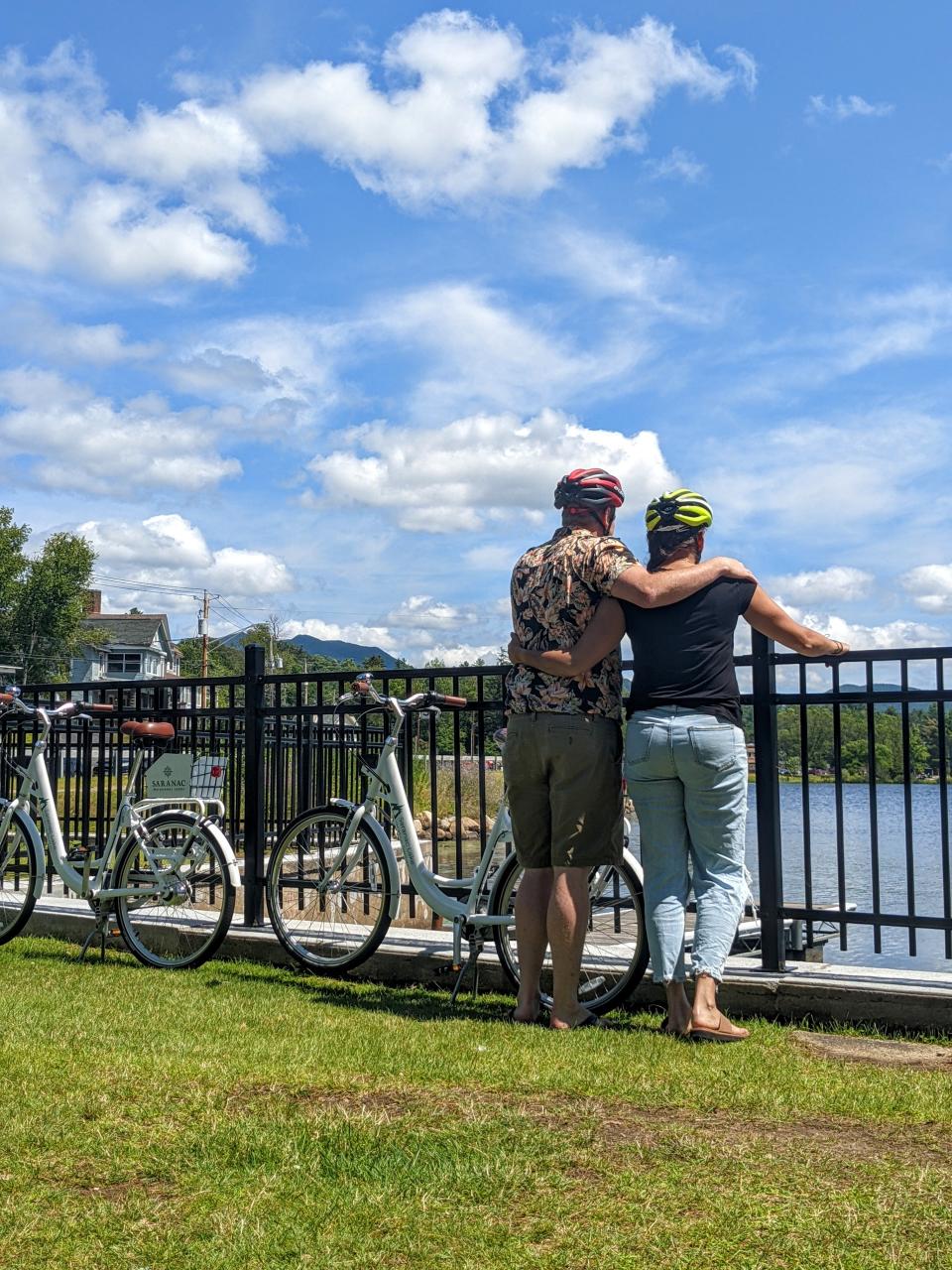 A couple overlooks the water with bikes set down beside them.