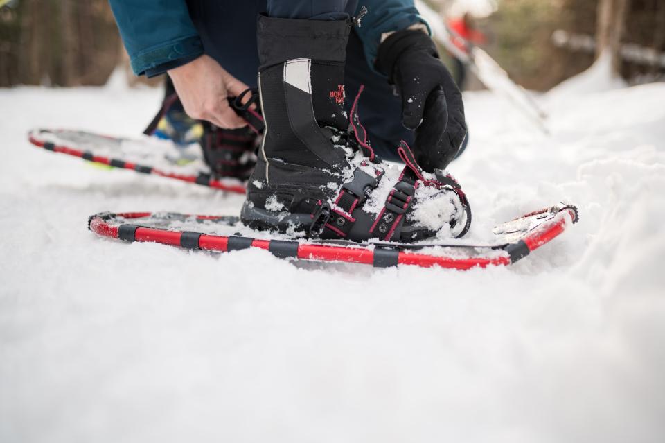 A close up show of someone straping on a snowshoe