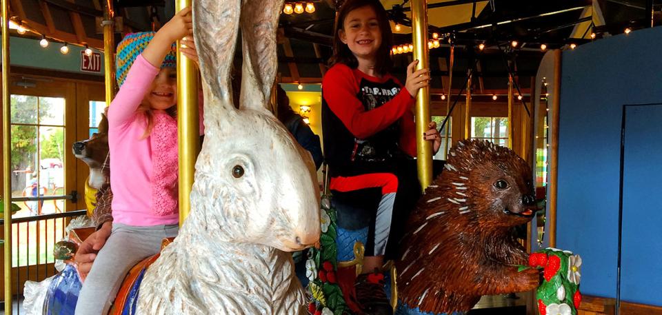 Smiling children riding on the Adirondack Carousel.