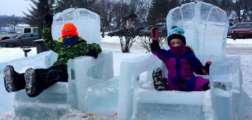 Two children sitting in ice chairs at the Ice Palace.