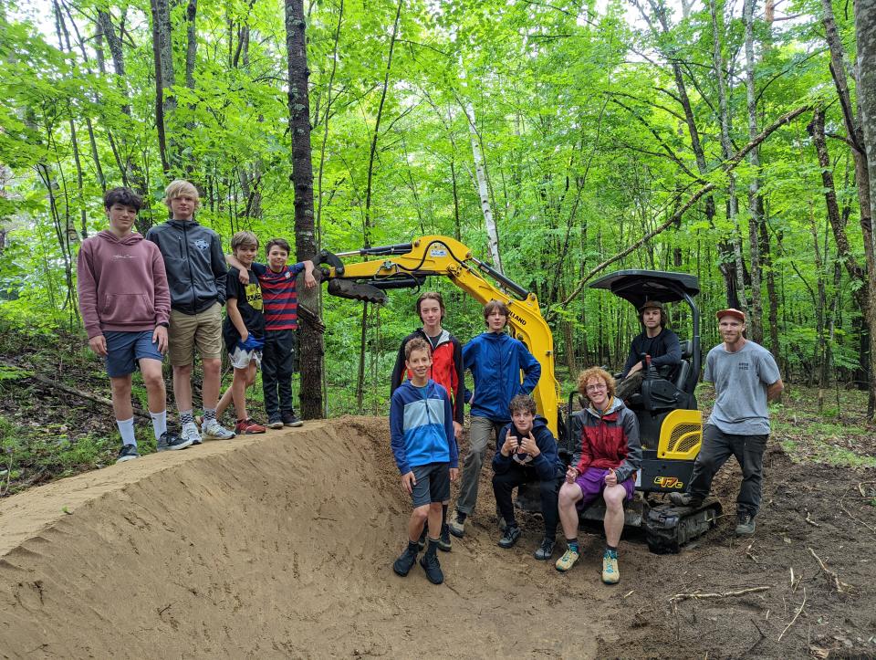 A group of young bikers pose next to an almost built pump track