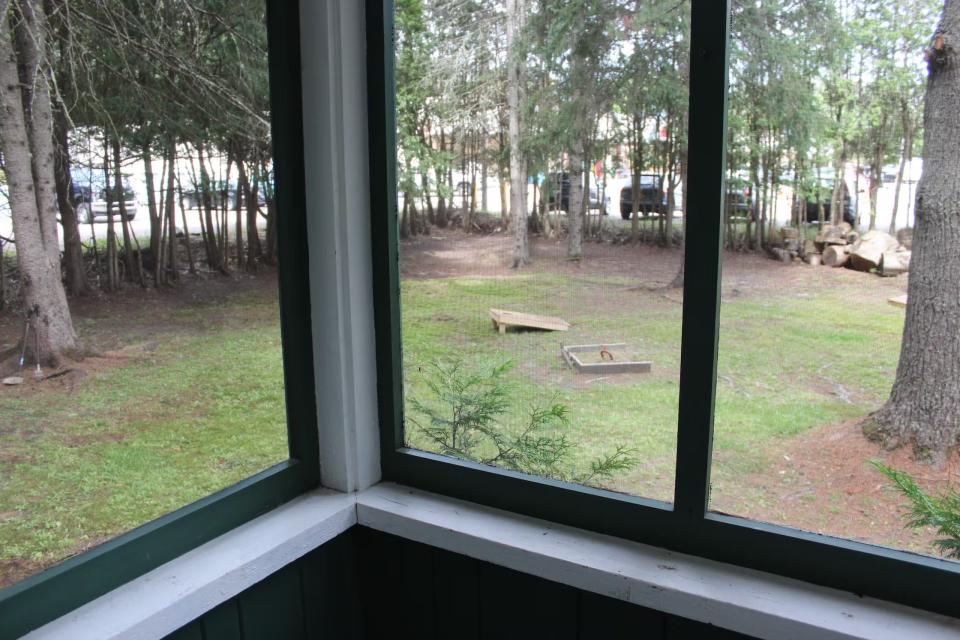 Looking out of a screened-in porch onto a grassy lawn.