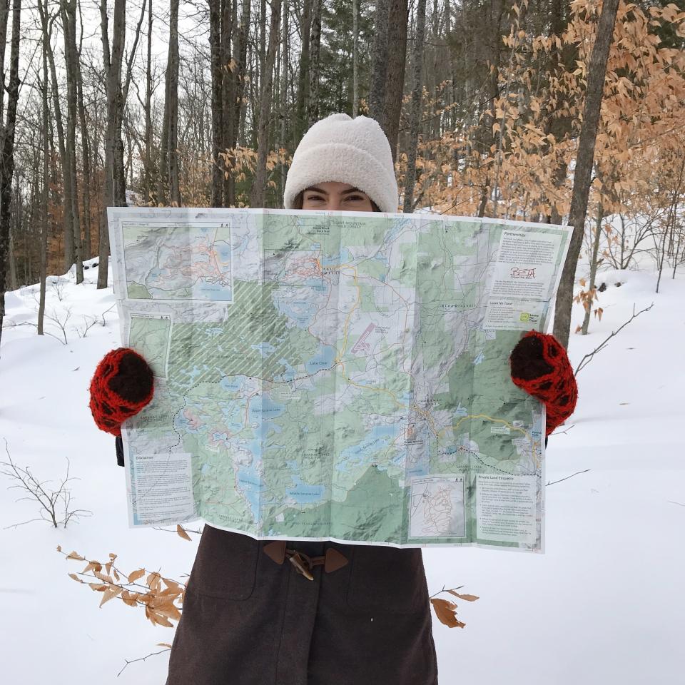 A woman holds up a map in the snow.