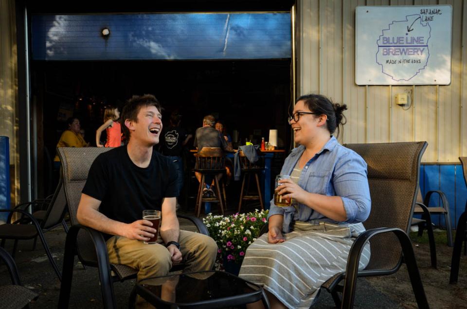 Two people laugh while enjoying beer outside a brewery