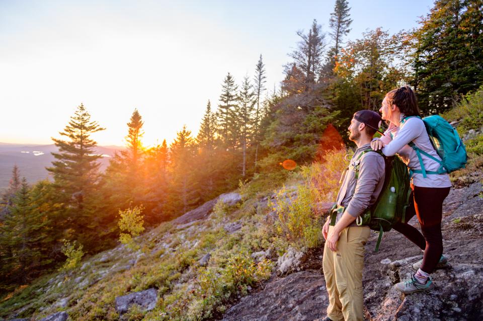 Two hikers enjoy a fall sunset on a mountain