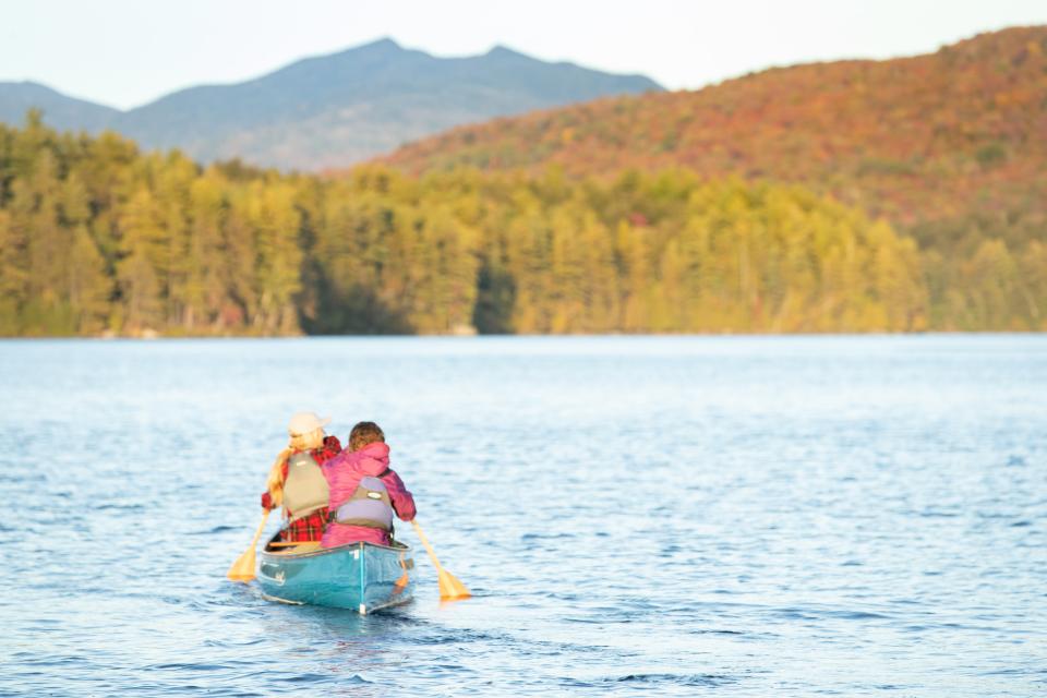 Two people in a canoe paddle out onto a lake.
