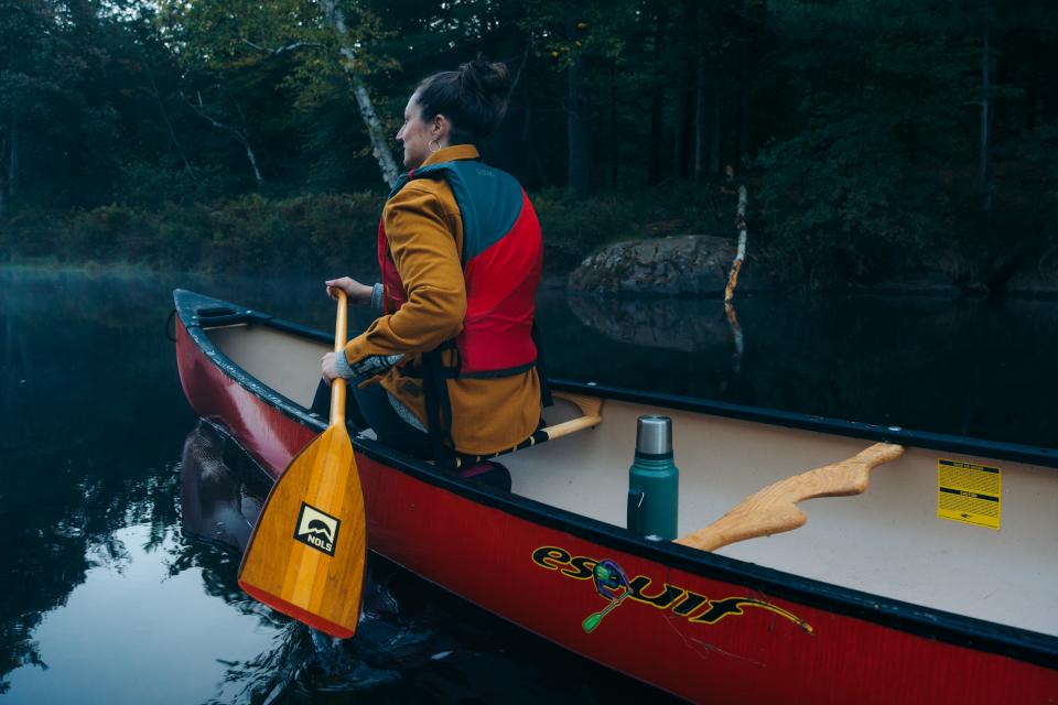 A woman paddles in a canoe.