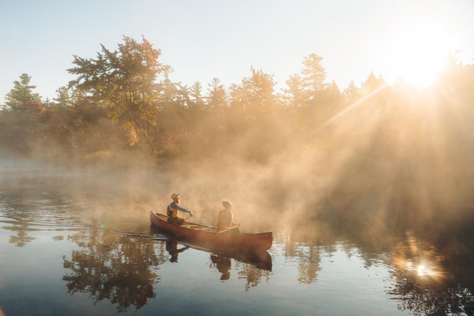 Two people paddle a canoe in early morning mist