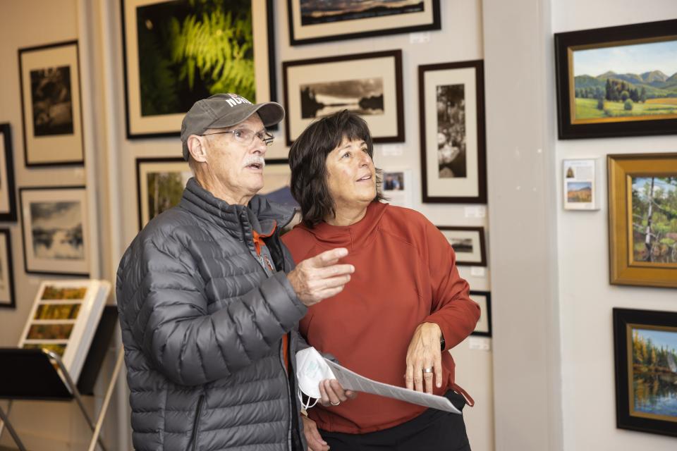 Two people point at art on the wall