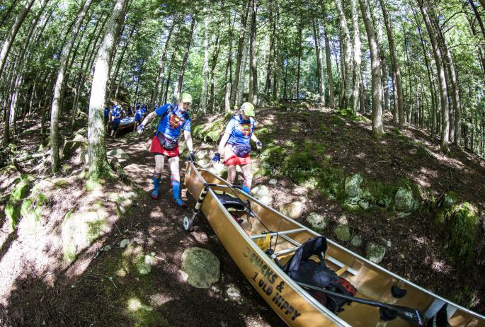 A team navigates one of the carries with their canoe in the Adirondack Canoe Classic