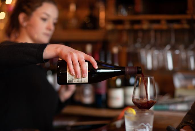 A bartender pours a glass of red wine at one of Saranac Lake's bars