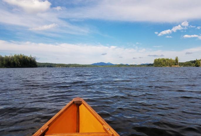 Photograph from a paddler's point of view on a lake with mountains and forests in the background