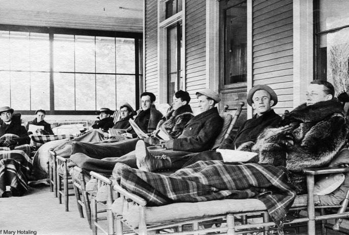 Vintage black and white photo of men on cure chairs at a Saranac Lake sanatorium.