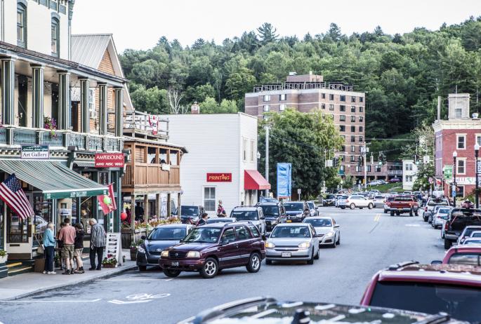Cars are seen driving past businesses in downtown Saranac Lake
