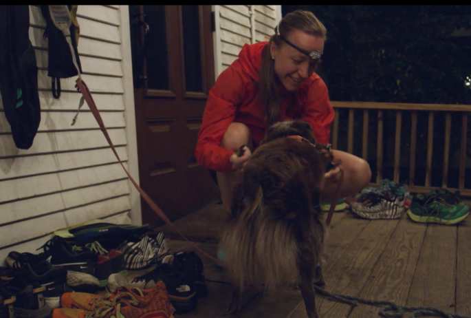 A woman puts a collar on a dog as they prepare to run together