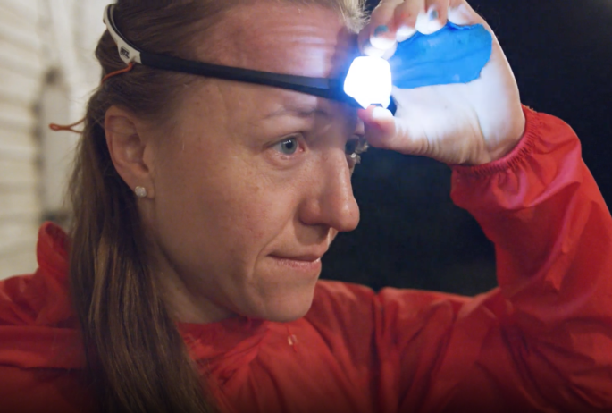 A woman turns on a headlamp in the dark
