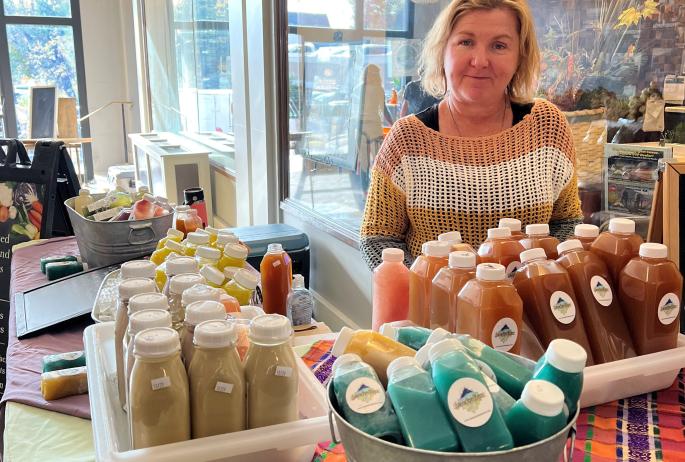 A woman stands behind a counter with baskets of smoothies on top of it.