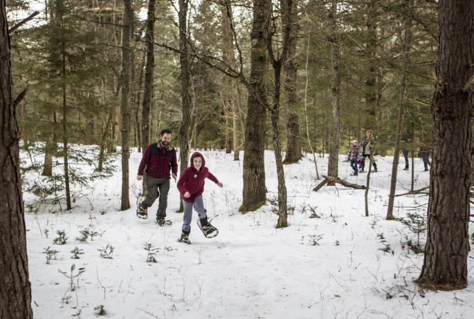 A family on a snowshoe hike, the leader a young boy grinning from ear to ear