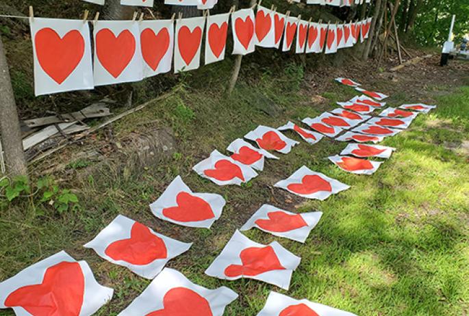 Hearts for the Heart Banner Project strung on a clothesline and lay on the grass on a sunny day.