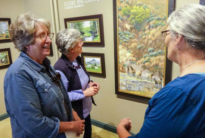 artist Sandra Hildreth (right) shares some interesting stories about the paintings
