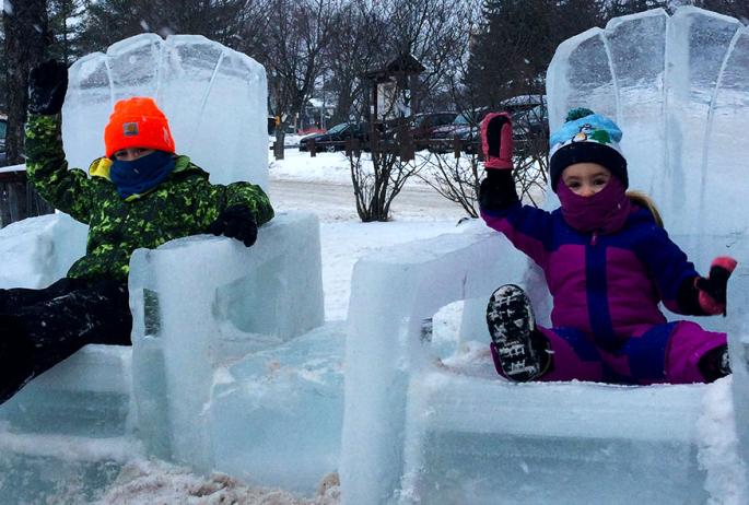 Two children sitting in ice chairs at the Ice Palace.