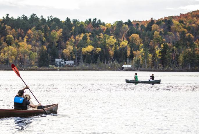 Two canoes participating in the 'Round the Mountain Canoe Race with beautiful fall foliage in the background.
