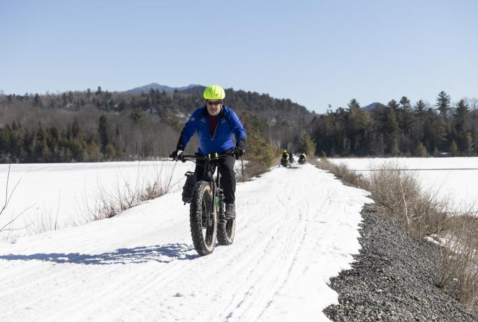 A fat-tire biker rides on a winter rail trail