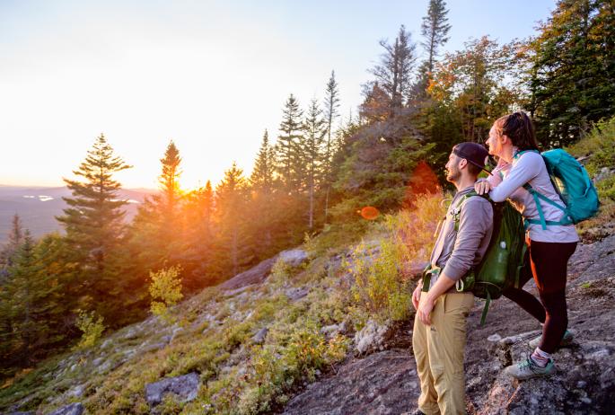 Two hikers enjoy a fall sunset on a mountain