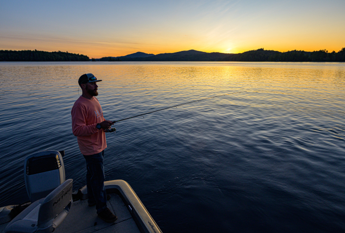 man fishing at sunset. Mountains in the background