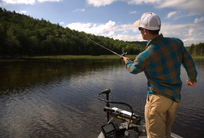 man in flannel fishing from bow of boat