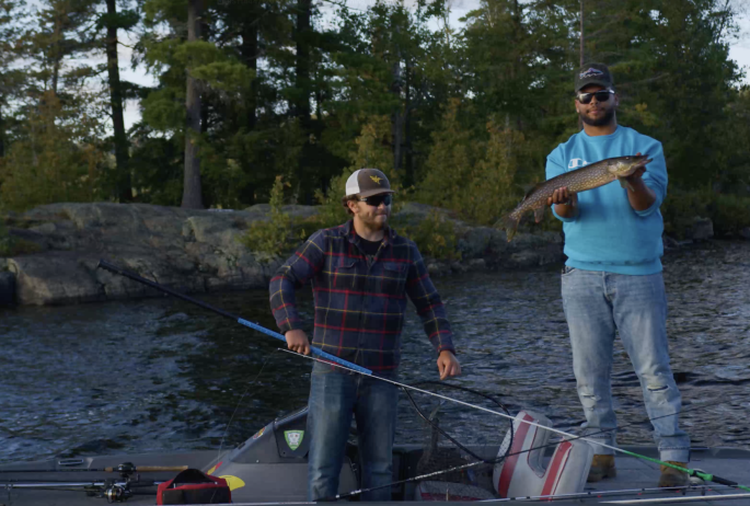 Two men on boat showing off large Pike