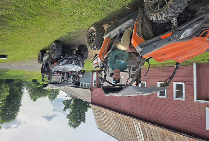 Man sitting in an orange UTV in front of Red Barn.