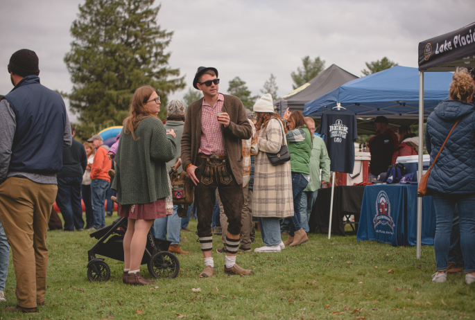 a man in german traditional clothes enjoys a fall market.