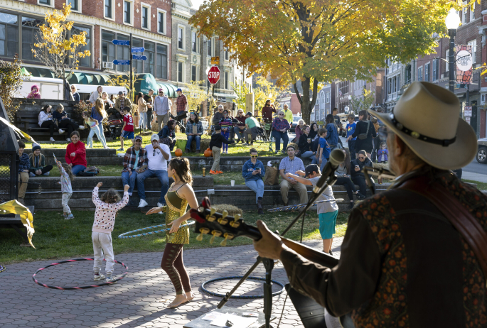 A man plays guitar for a crowd of people dancing in a park.