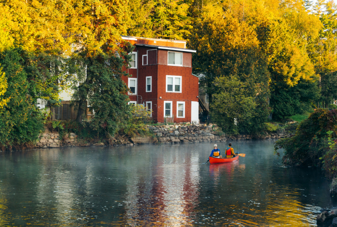 Two people paddling a canoe through Saranac Lake on the Saranac River.