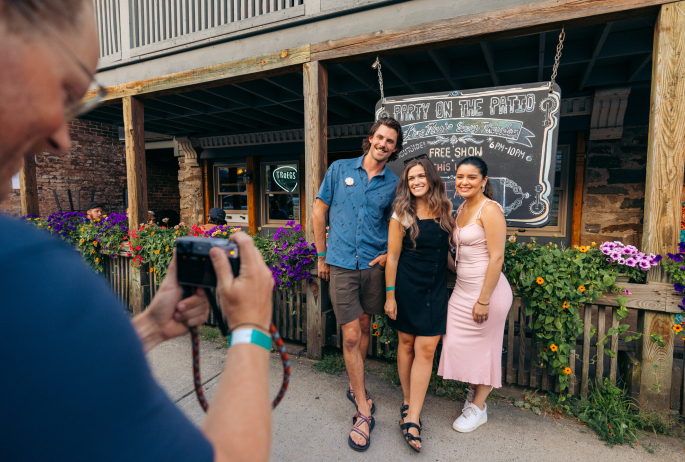 A group of friends smile and pose for a picture in front of a restaurant.