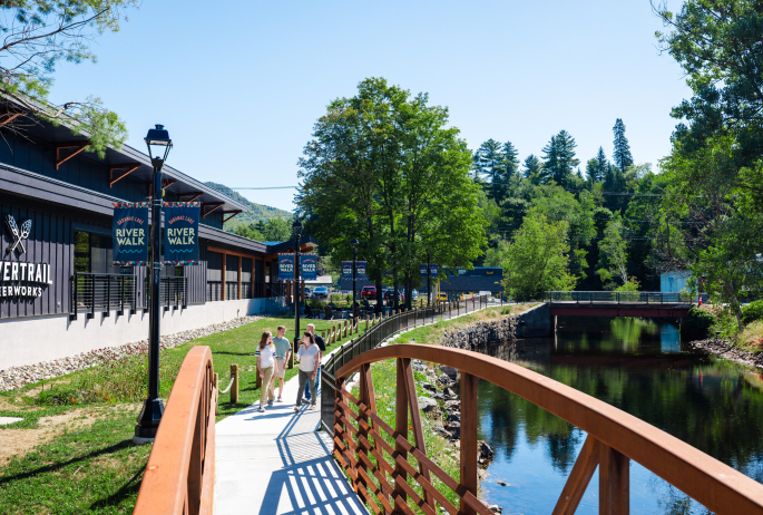 A family walks a trail along a river and brewery.
