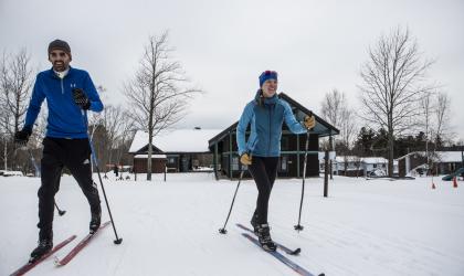 Couple skiing at view of the Dewey Mountain Lodge in the background.