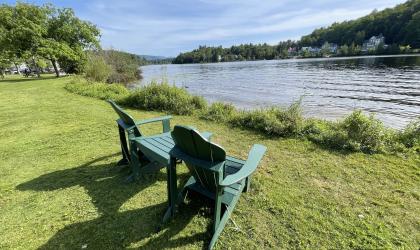 two adirondack chairs on the edge of a lake