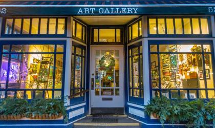 Exterior of the Adirondack Artists Guild gallery with its large storefront windows lit up from the inside