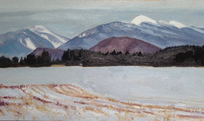A snowy field with white capped mountains in the background
