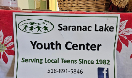 A table with a paper sign with Saranac Lake Youth Center