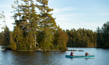 Two paddlers passing one of the smaller Saranac islands in a canoe.