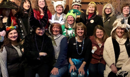 A group of smiling women wearing silly hats and carnival beads